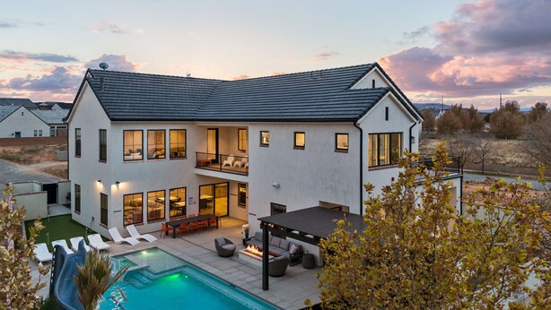 Une maison à deux étages dotée d’une piscine, d’un espace salon extérieur et d’un patio couvert.