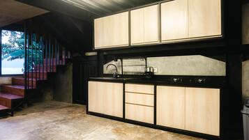 A modern kitchen with wooden cabinets, a black countertop, and a stainless steel sink.