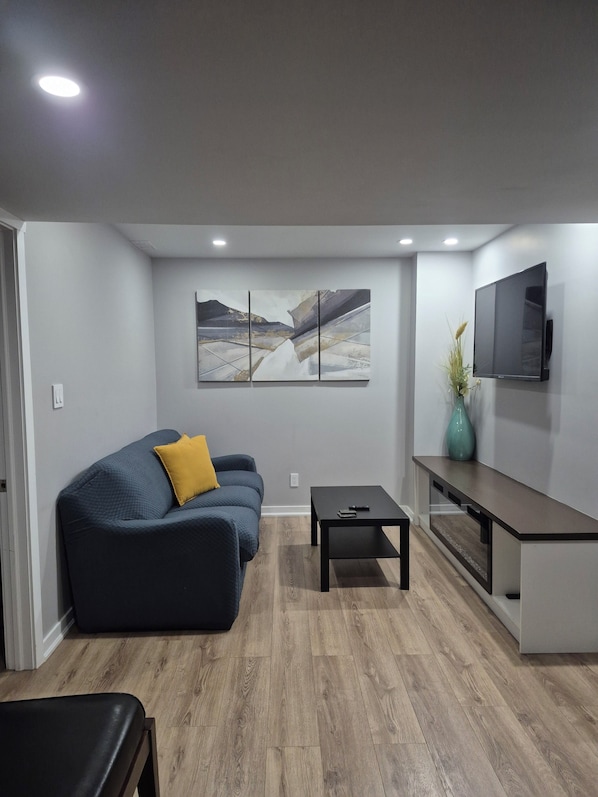 A modern living room with a sofa, a coffee table, a TV, and a painting on the wall.