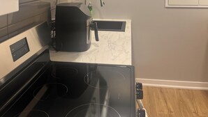 Ett modernt kök med en svart spis, vita skåp och en inbyggd mikrovågsugn.