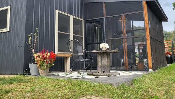 A modern building with large windows and a covered outdoor seating area. - Mee Mee's Cabin Retreat- River, nature, small town, Hot Tub
 (Genoa)