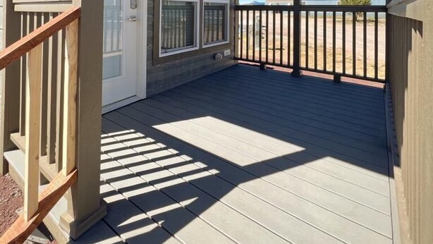 Eine überdachte Terrasse mit Blick auf den Strand, Holzgeländer und einer Tür zu einem Innenbereich.