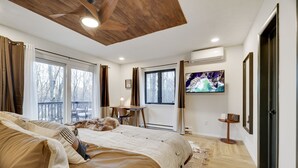 Un dormitorio con una cama grande, un escritorio, una silla, un televisor y una ventana con cortinas.