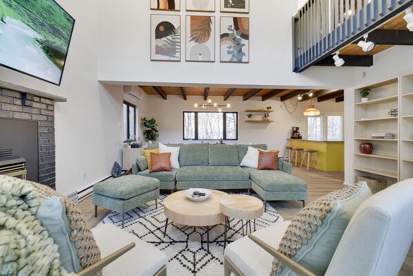 A spacious living area with a sectional sofa, round coffee tables, and a fireplace.