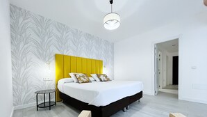 Ein modernes Schlafzimmer mit einem großen Bett, einem Nachttisch und einem Sessel.