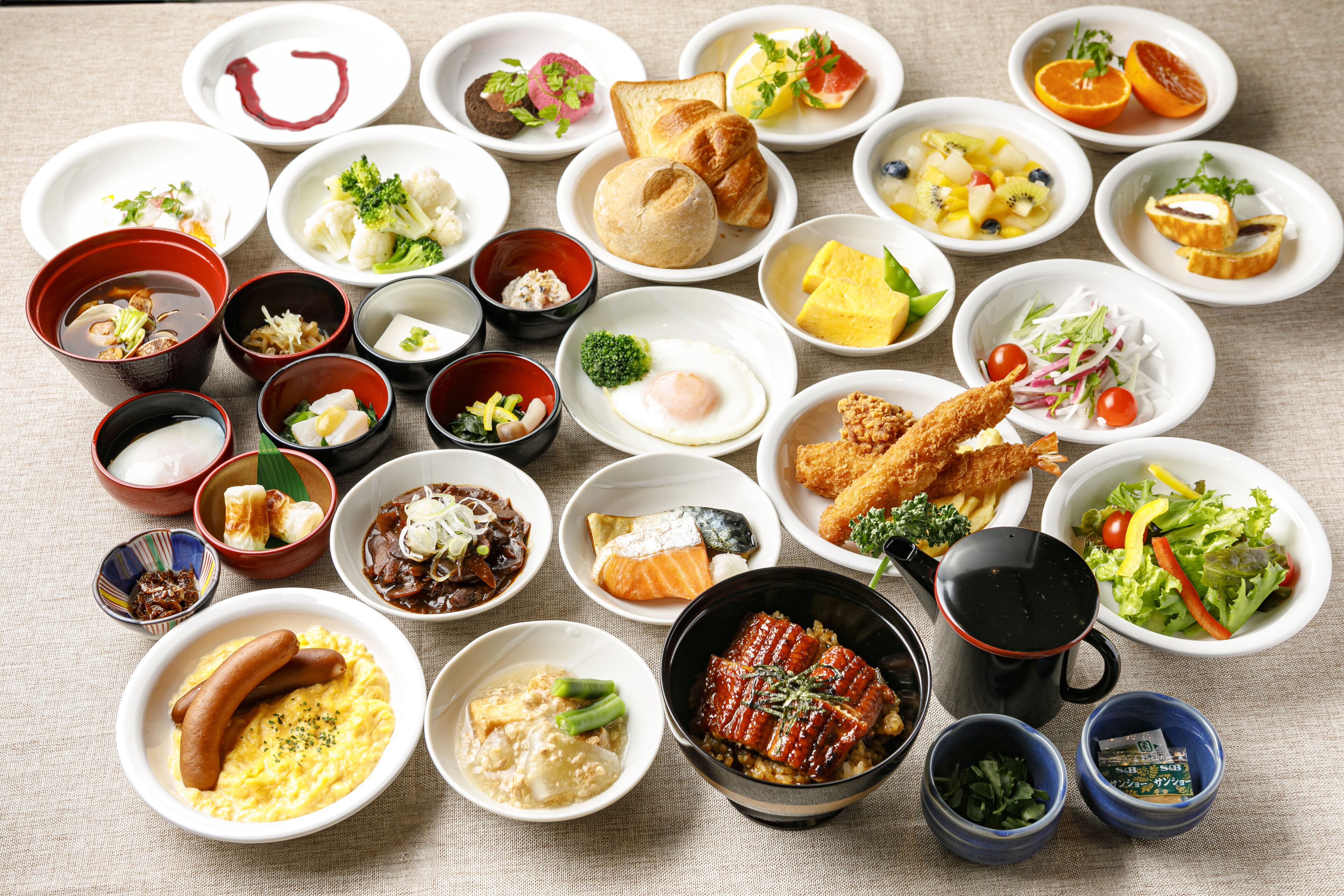 A variety of dishes arranged on a table, including sushi, sashimi, and other Asian cuisine.