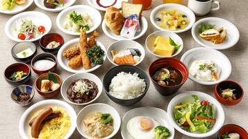 A variety of dishes including sushi, rice, and various salads spread across multiple bowls and plates.