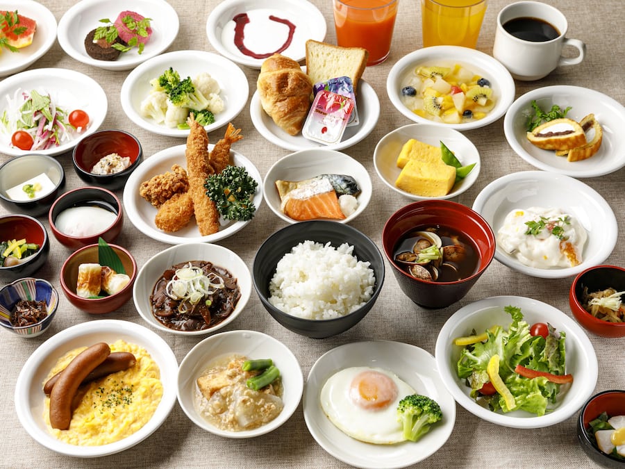 A variety of dishes including sushi, rice, and various salads spread across multiple bowls and plates.