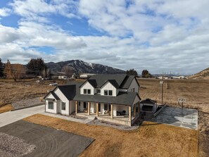 A modern two-story house with a covered patio and a view of mountains in the background. - Hot tub, Sports Court, Theater, Game Room, Firepit (Lava Hot Springs)
