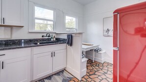 Eine Küche mit weißen Schränken, einer Granit-Arbeitsplatte, einem roten Kühlschrank und einem Fliesenboden.