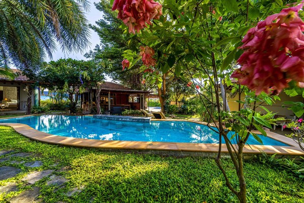 A swimming pool surrounded by lush greenery and a wooden structure. - Secluded Oasis for Family - BM5 (Hua Hin)