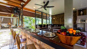 Een moderne keuken met een aanrecht van natuursteen, een houten bar en een plafondventilator.