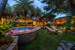 A pool area with lounge chairs, a hot tub, and a stone wall. - Secluded Oasis for Family - BM5 (Hua Hin)