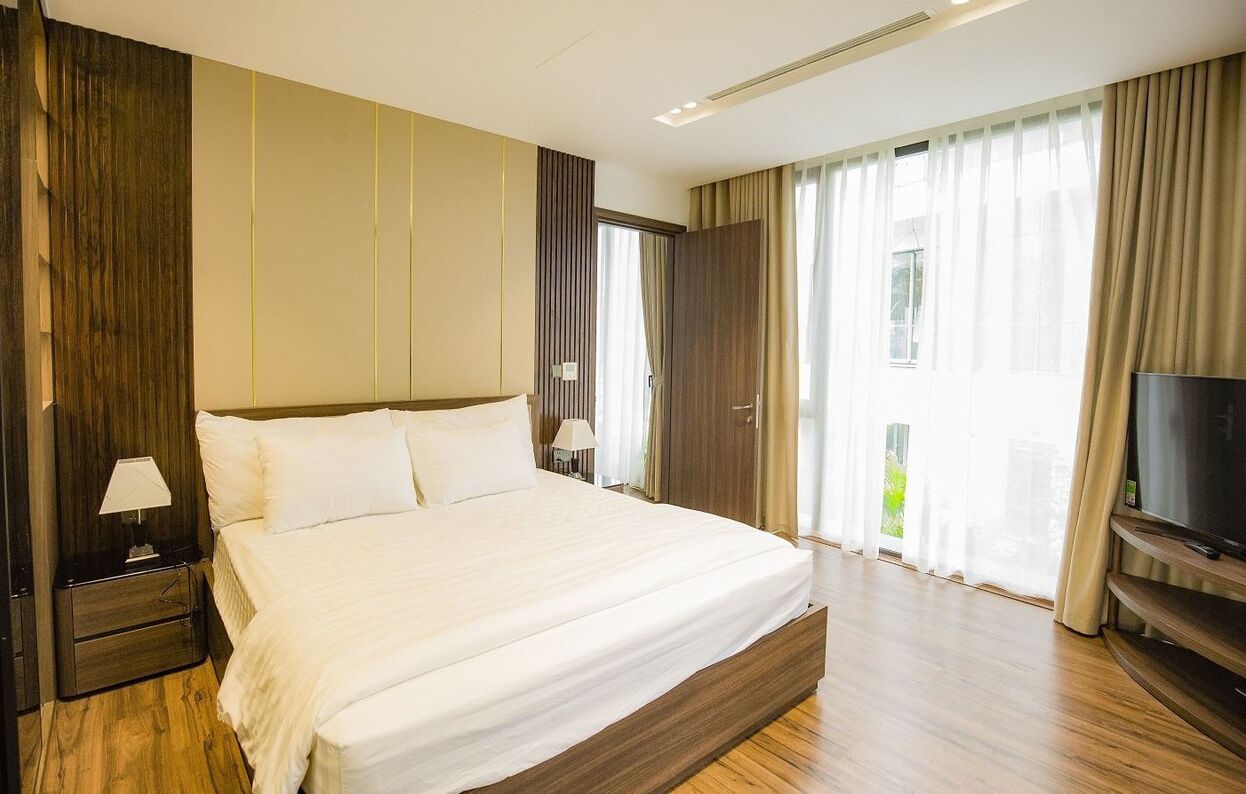 Une chambre d’hôtel avec un grand lit, une télévision et un balcon avec des rideaux.