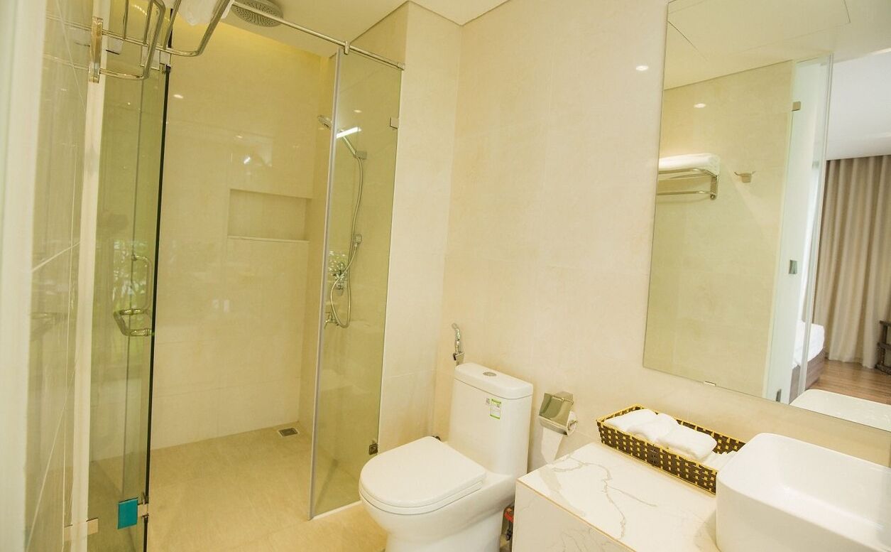 Ein modernes Badezimmer mit einer gläsernen Duschkabine, einer Toilette und einem Waschbecken mit Marmorplatte.