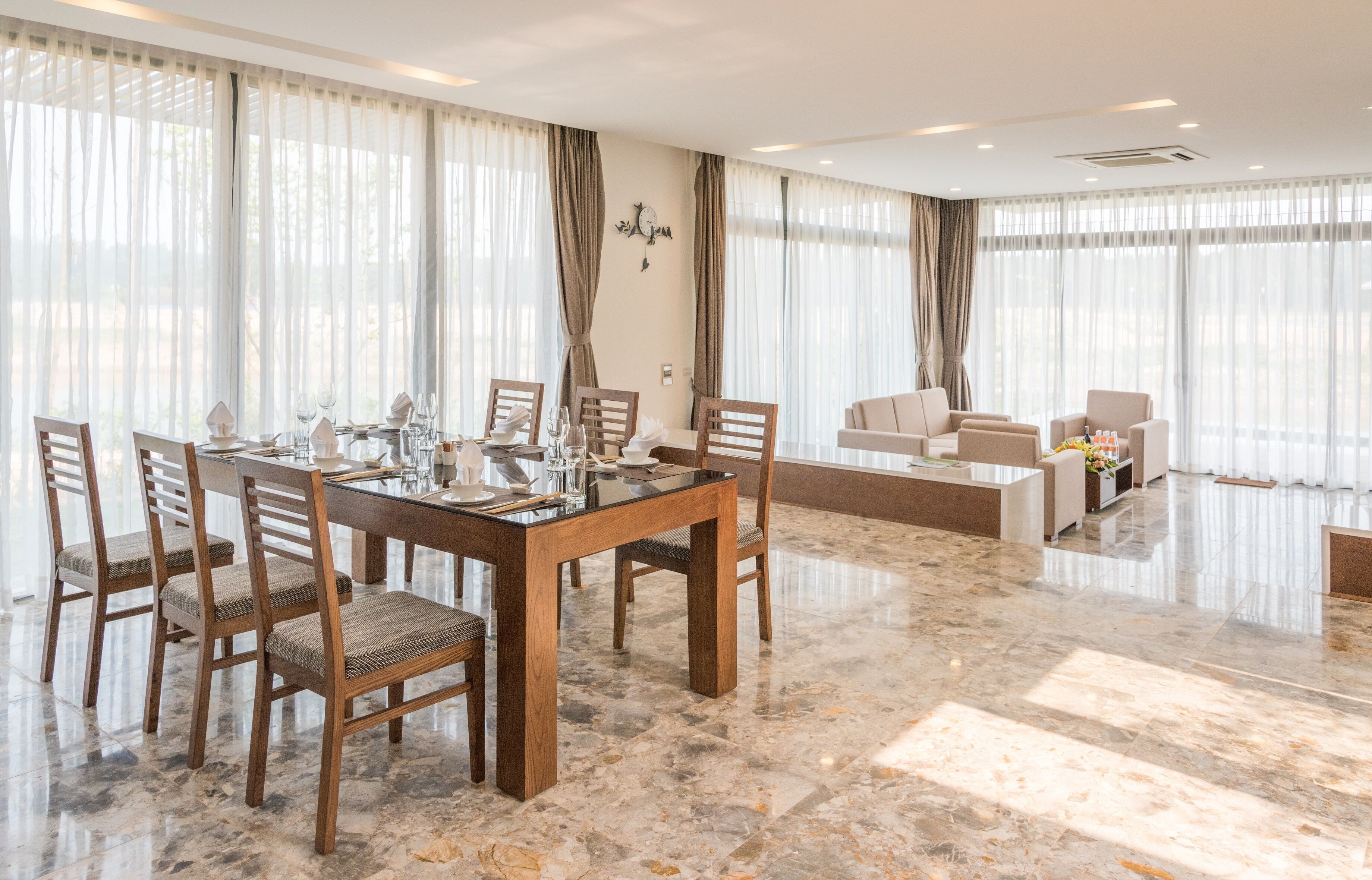 A modern dining area with a marble floor, wooden table, and chairs.