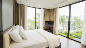Habitación de hotel moderna con una cama grande, un televisor de pantalla plana y amplios ventanales que ofrecen vistas al exterior.
