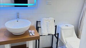 A bathroom with a white sink, a mirror with blue lighting, a toilet, and a towel rack. - Hotel Aoki valle de ángeles  (Valle de Angeles)