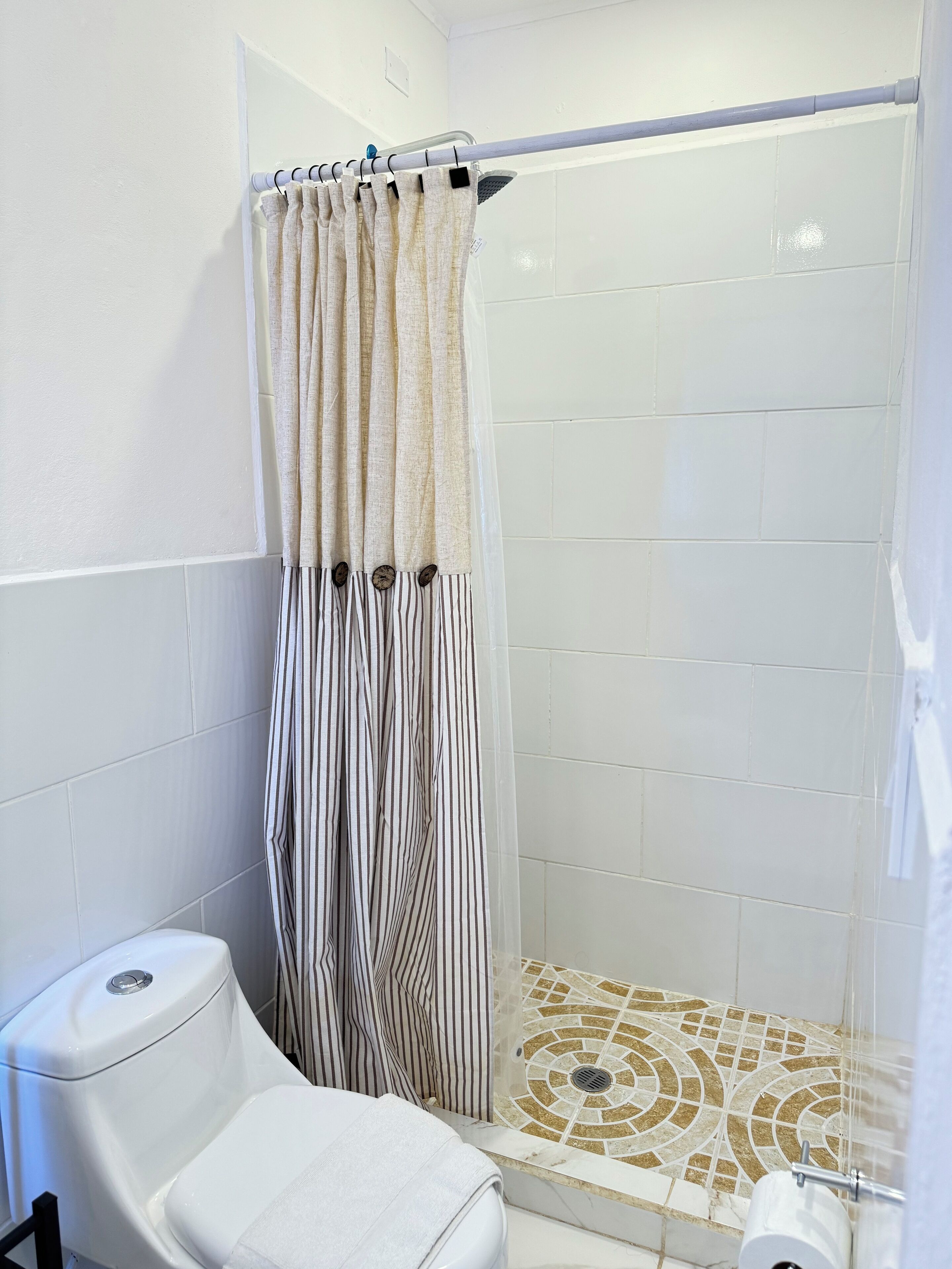 A bathroom with a shower, toilet, and a towel rack.