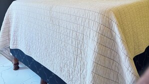 A bed with a quilted bedspread, a black pillow, and a white headboard. - Hotel Aoki valle de ángeles  (Valle de Angeles)