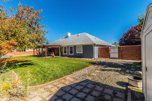 A residential backyard with a lawn, a patio area, and a brick wall. - Northern New Mexico Home Perfectly Located!   (Aztec)