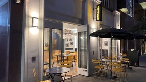 An outdoor seating area with tables and chairs, a glass door entrance, and a sign above the door. - Condesa Residence Campeche 8 (Ciudad de México)