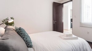A bedroom with a bed, pillows, a bedside lamp, and a door leading to another room. - Condesa Residence Campeche 8 (Ciudad de México)