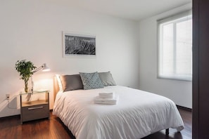 Une chambre à coucher avec un lit, une table de chevet, une lampe et un tableau encadré au mur.