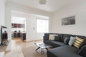 Un salon moderne avec un canapé, une table basse et une vue sur la cuisine et la salle à manger.