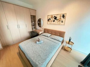 Un dormitorio con cama, un escritorio, un armario y una pequeña mesa redonda con una planta.