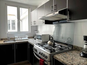Une cuisine équipée d’une cuisinière à gaz, d’un four à micro-ondes et de meubles de rangement en acier inoxydable.