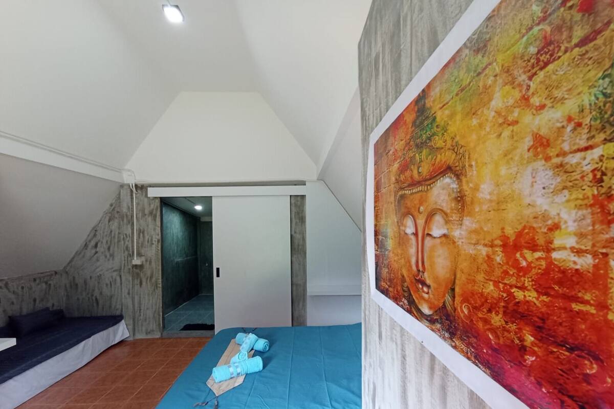 A room with a bed, a painting, and a view of a staircase.
