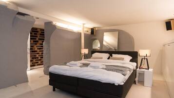 Een moderne slaapkamer met een groot bed, bedlampen en een ingebouwde wijnrek.