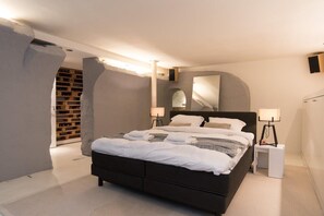 Un dormitorio moderno con una cama grande, lámparas de noche y una estantería empotrada para vinos.