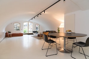 A spacious living area with a round dining table, black chairs, and a sofa.