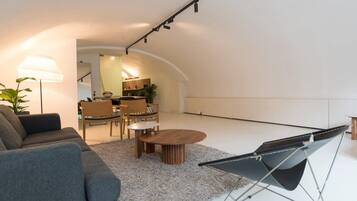 Een moderne woonkamer met een bank, een salontafel en een fauteuil die kan worden omgeklapt.