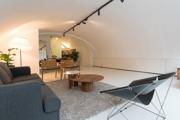 Una sala moderna con un sofá, una mesa de centro y un sillón convertible.