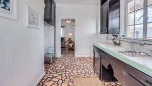 A narrow hallway with a mosaic floor leading to a kitchen area with a sink and a window. - 1926 Original Firehouse / Close to U of A / Loft (Tucson)
