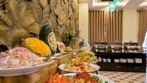 Een buffet met diverse gerechten, een houten wand met een structuur en een modern interieur met een kroonluchter.