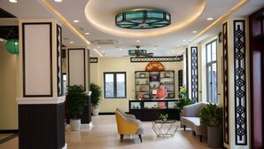 Een lobby met een receptiebalie, zithoek, decoratieve wandpanelen en een plafondventilator.