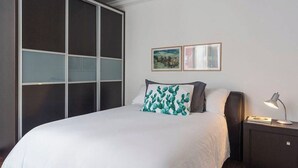 A bedroom with a bed, a nightstand, a lamp, and a sliding door closet. - Condesa Residence Campeche 11 (Ciudad de México)