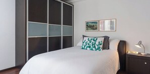 Una camera da letto con un letto, un comodino, una lampada e un armadio con ante scorrevoli.