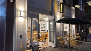 An outdoor seating area with tables and chairs, a glass door entrance, and a sign above the door. - Condesa Residence Campeche 11 (Ciudad de México)
