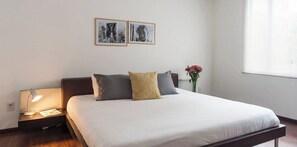 Une chambre à coucher avec un lit, une lampe de chevet et deux tableaux encadrés accrochés au mur.