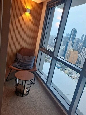 A balcony with a view of a cityscape, a chair, and a small round table. - Bona Travel Haeundae (Busan)