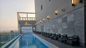 Une piscine avec des chaises longues et un panneau indiquant une ouverture prochaine.