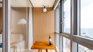 Une chambre moderne avec une table en bois, une bouteille de vin et une vue sur la ville à travers de grandes fenêtres.