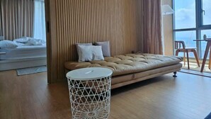 Une chambre d’hôtel moderne avec un grand lit, un canapé, une table ronde et une vue sur le ciel.