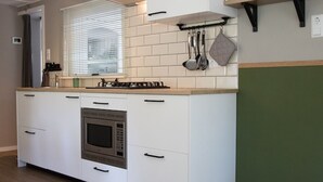 A modern kitchen with white cabinets, a built-in oven, and a window with blinds.