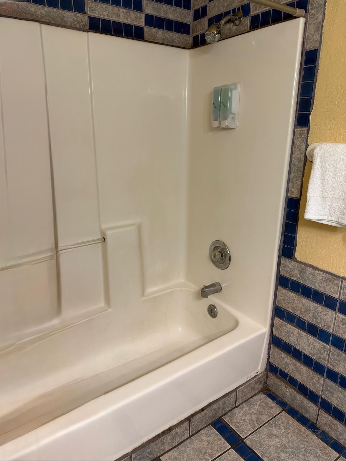 A bathtub with a showerhead, a towel rack, and a tiled wall.